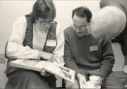 Three members sitting and viewing a book at "the Blessing of the Office of Dignity/Central PA" - March 18, 1990