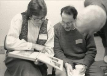 Three members sitting and viewing a book at "the Blessing of the Office of Dignity/Central PA" - March 18, 1990