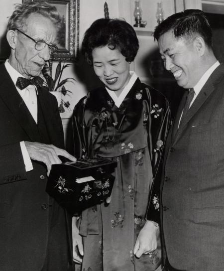 Three people look at ornate box, c.1960 
